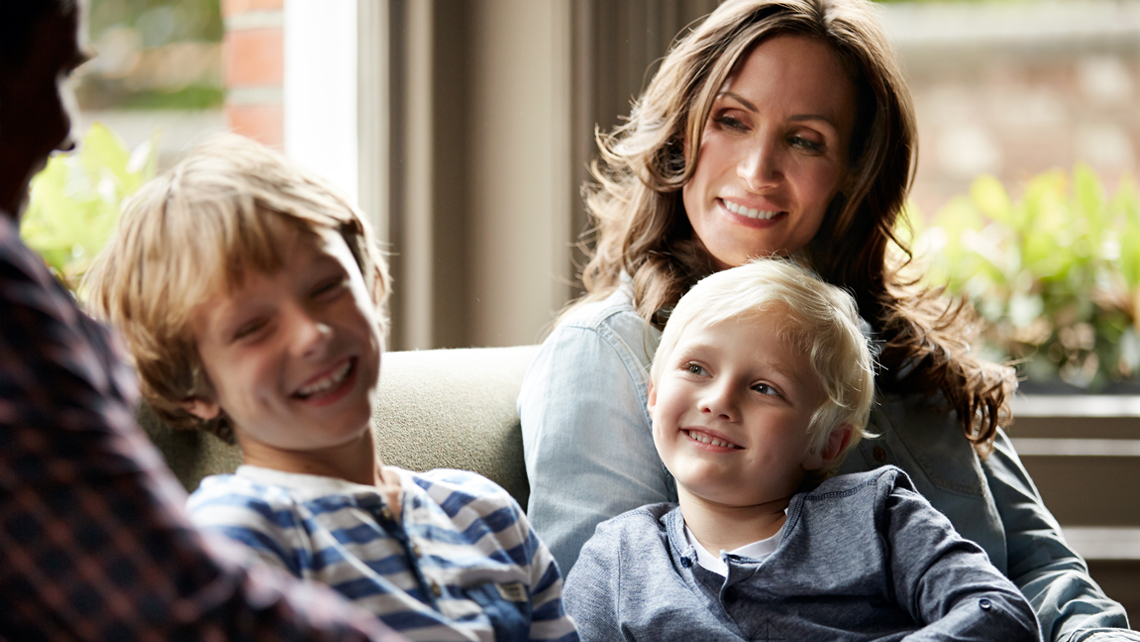 Young couple with two young sons, sitting on a couch